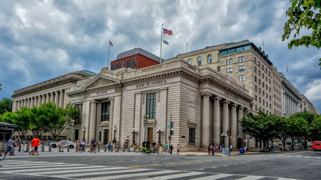 A classic architectural bank building under a dramatic sky in a bustling city environment.