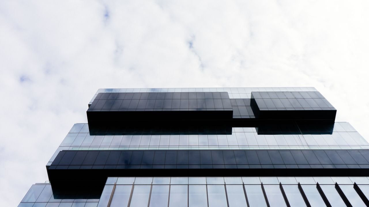 Contemporary building with a glass facade and geometric patterns, low angle view.