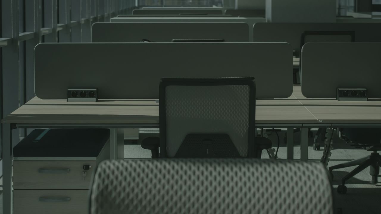 A sleek modern office with multiple desks and chairs, showcasing an empty and orderly workspace.