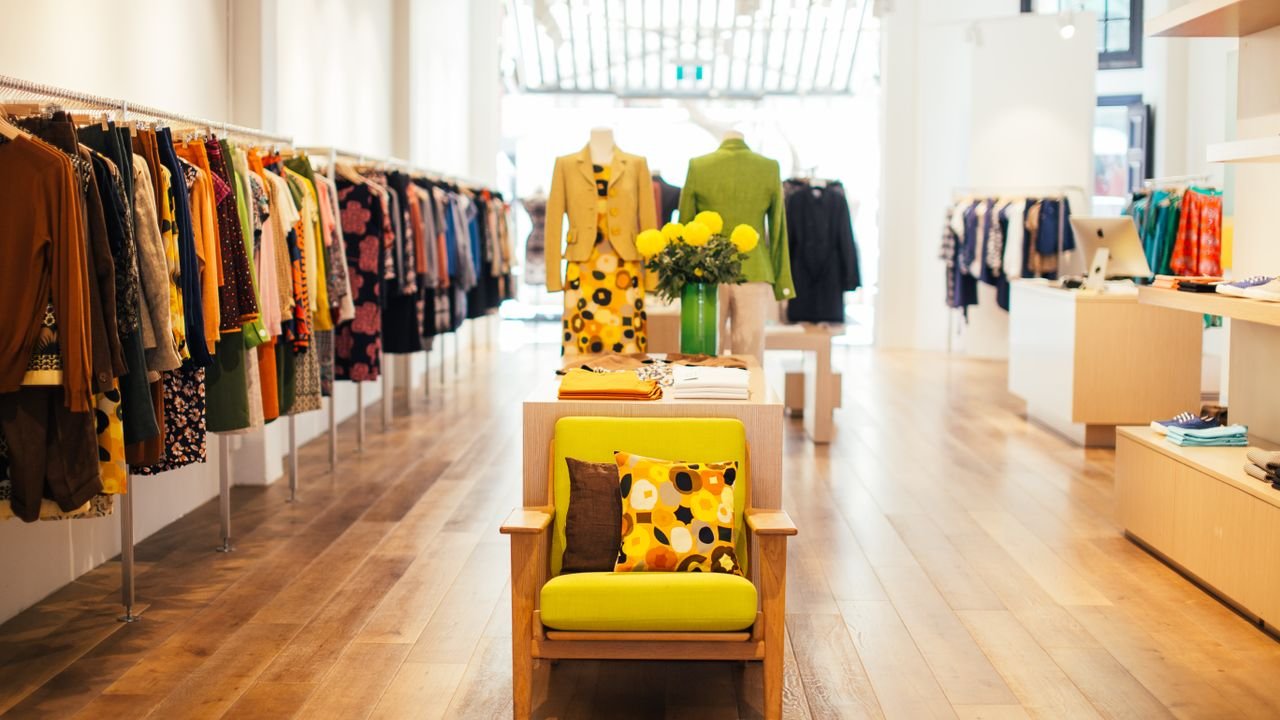 Interior of modern fashion store with stylish colorful clothes handing on rack in daytime