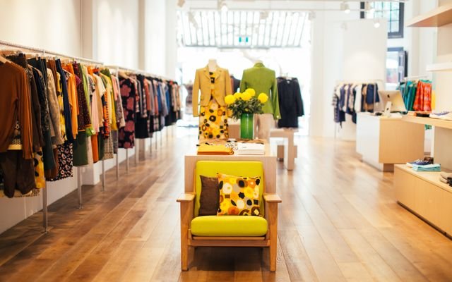 Interior of modern fashion store with stylish colorful clothes handing on rack in daytime