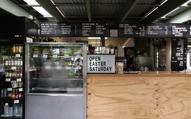 A trendy café interior featuring menu boards, a display case, and a wooden counter.