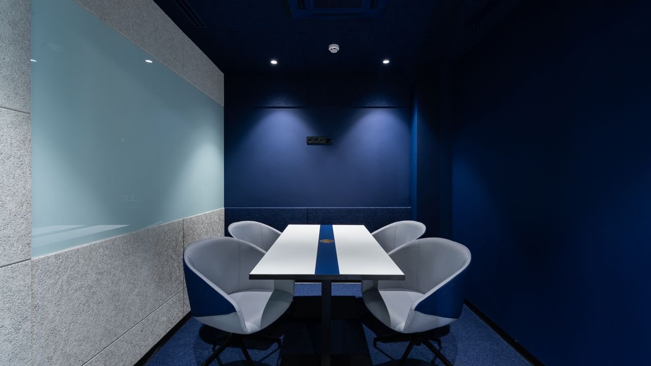 Comfortable chairs placed on carpet at long white desk in modern conference room with blue walls in contemporary business center