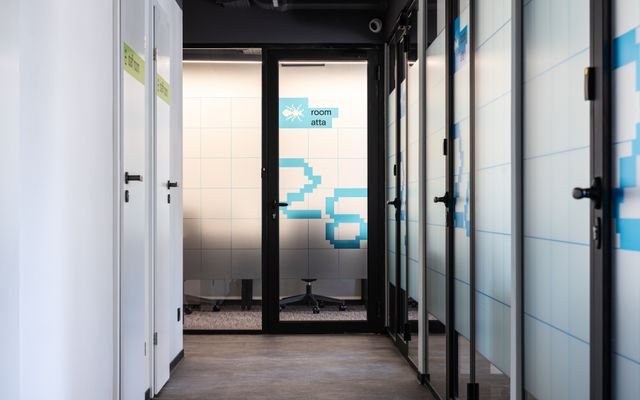 Hall with white and glass translucent walls and blue numbers on doors of various contemporary offices in modern business center
