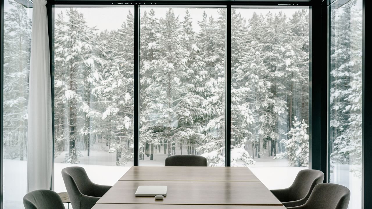 Elegant conference room featuring large windows with a snowy forest view, perfect for serene business meetings.