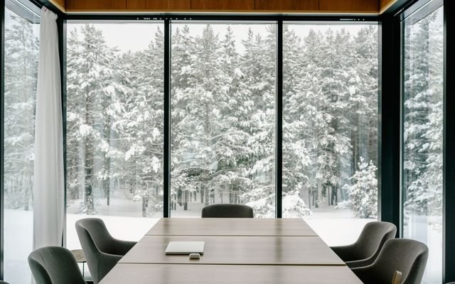 Elegant conference room featuring large windows with a snowy forest view, perfect for serene business meetings.
