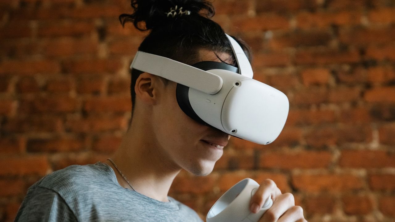 Side view of excited young male with hair bun holding controller while enjoying VR device