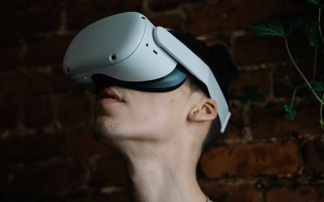 Young male wearing modern goggles of virtual reality and immersing in cyberspace while being in room with brick walls