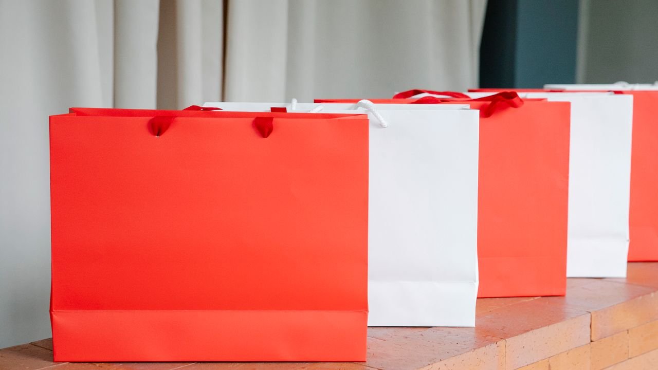 Set of red and white paper shopping bags placed on brick shelf in studio