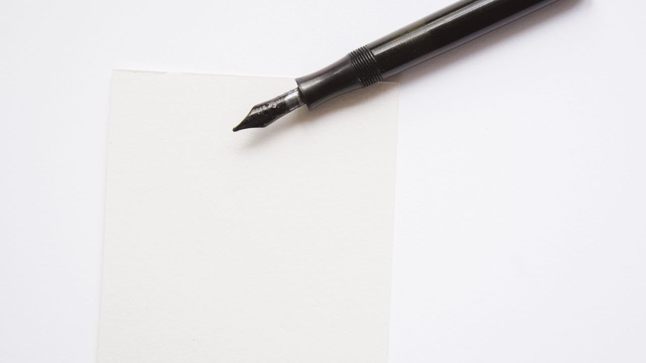A close-up image of an elegant fountain pen resting on blank white paper, perfect for writing themes.