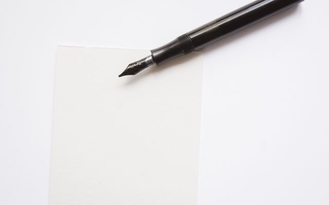 A close-up image of an elegant fountain pen resting on blank white paper, perfect for writing themes.