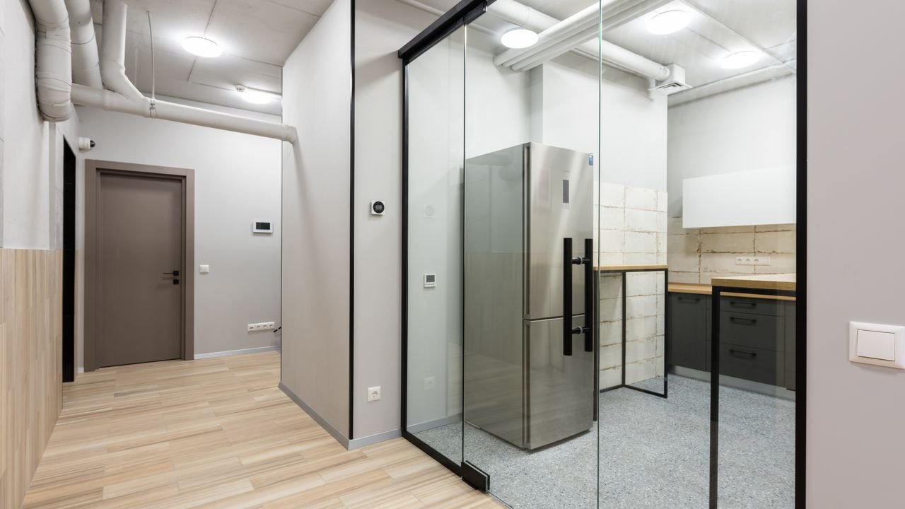 Interior of spacious hallway and kitchen with counters and appliances in contemporary workplace