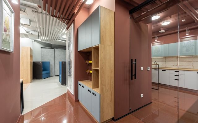 Corner of cabinet separating spacious workplace with new furniture and modern kitchen with counters and tiled floor