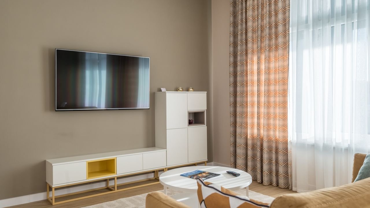 Cozy living room interior with beige walls, flat-screen TV, and stylish decor.