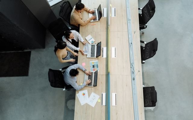 High angle view of colleagues working together on laptops in a modern office setting.