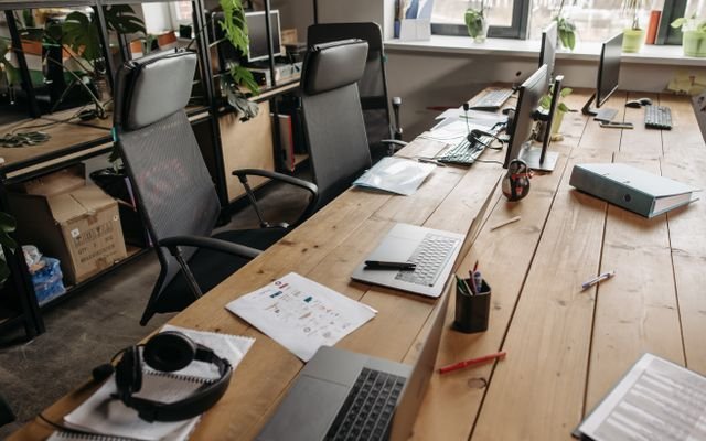 Spacious co-working office with wooden desks, laptops, and modern chairs.