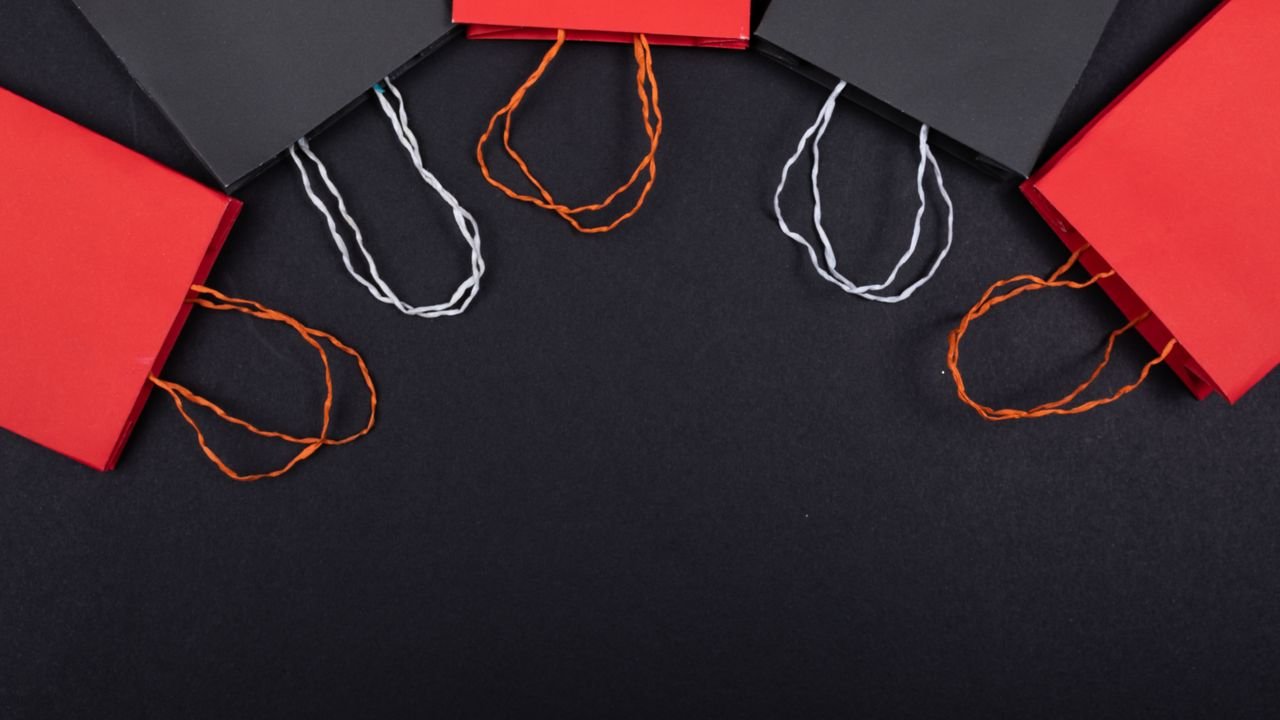 Flat lay of red and black paper bags on a black background with copy space.