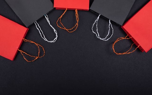 Flat lay of red and black paper bags on a black background with copy space.