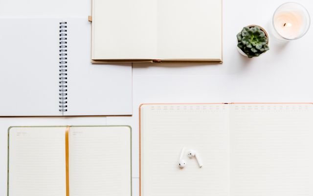 A clean flat lay of notebooks, planners, Airpods, and succulents, ideal for productivity themes.