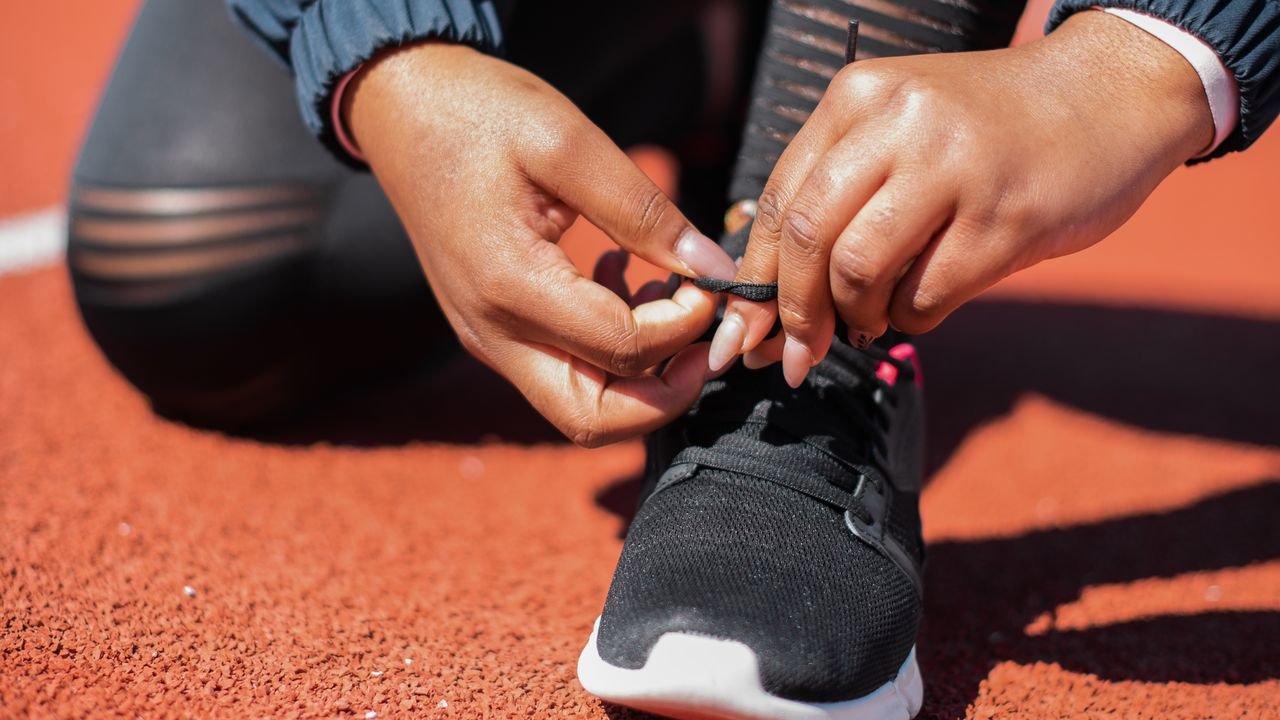 Close-up of athlete tying laces on sneakers on a running track, emphasizing readiness.