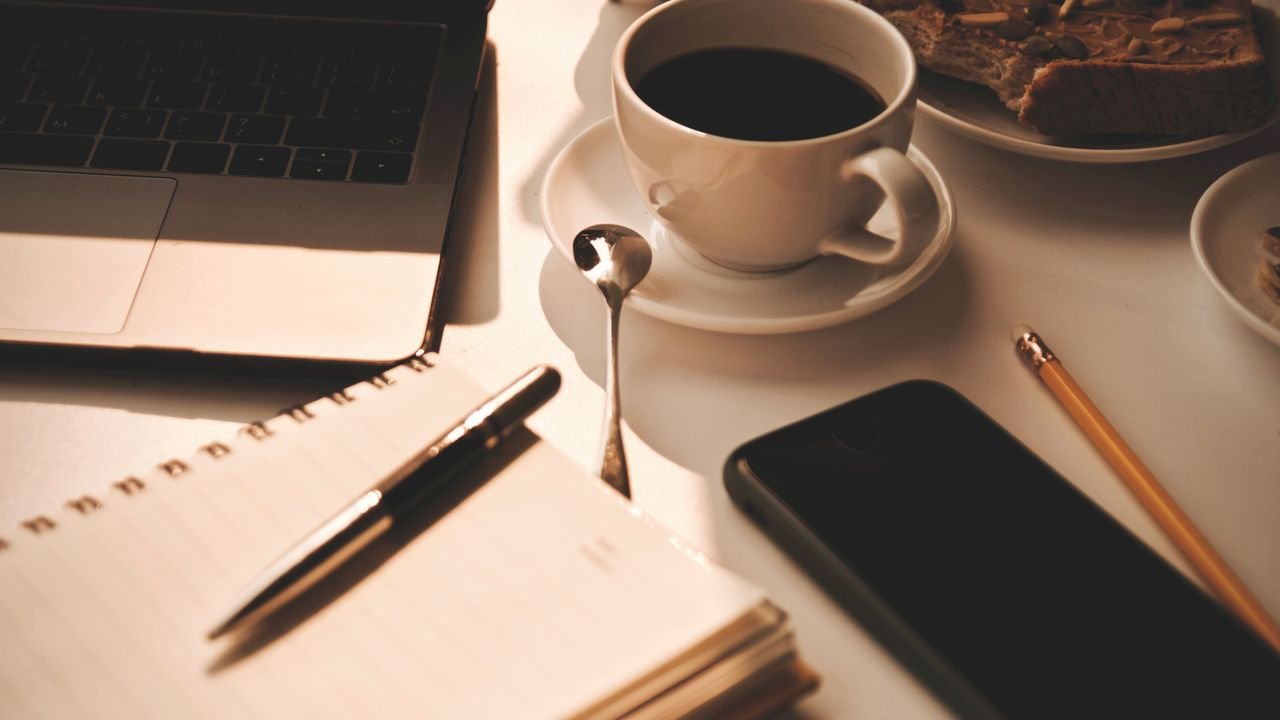 Warm and inviting workspace setup with coffee, notebook, and snacks, perfect for productivity.
