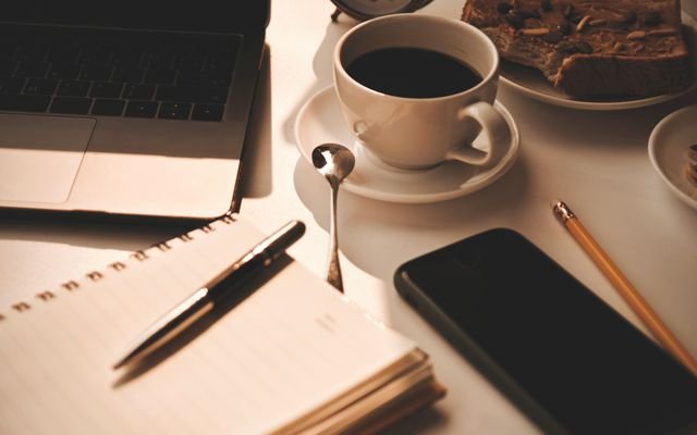 Warm and inviting workspace setup with coffee, notebook, and snacks, perfect for productivity.