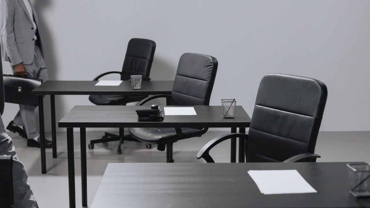 Contemporary office space with black leather chairs and desks, showcasing a minimalist design.