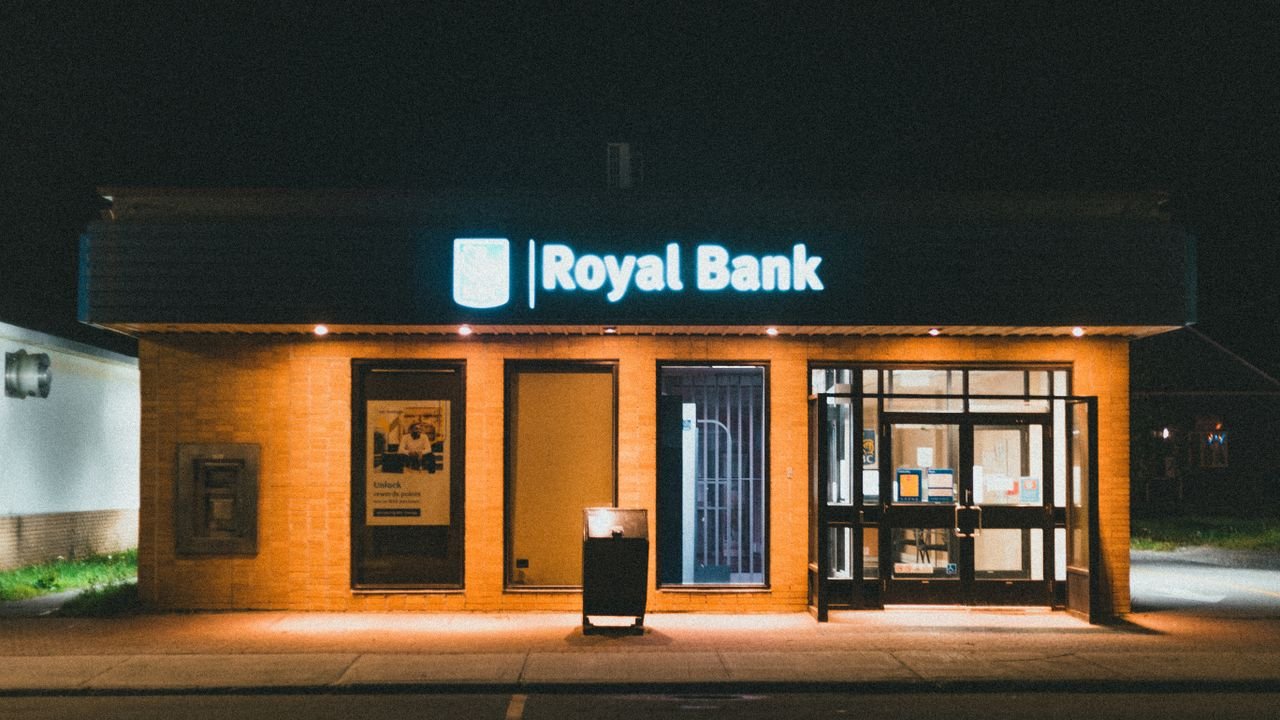 Exterior view of a Royal Bank building at night with glowing facade lights.