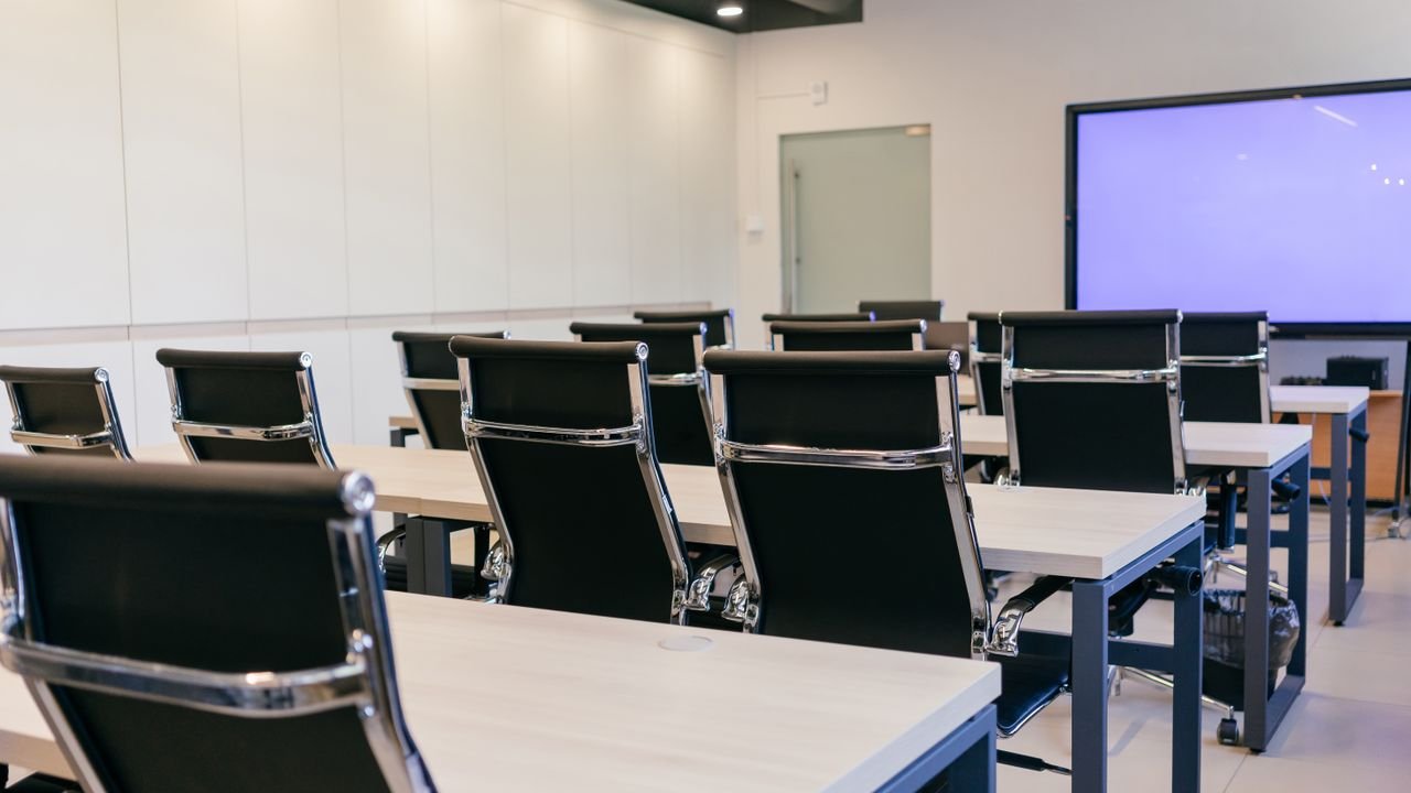 Spacious, modern conference room with black chairs and a projection screen.