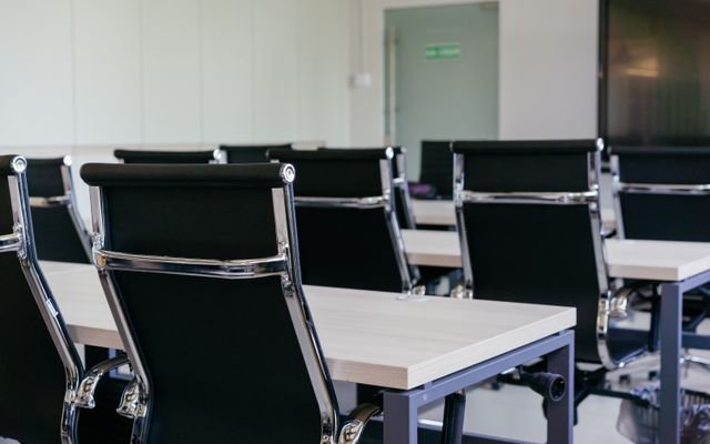 Sleek modern conference room with black chairs and white desks, suitable for business meetings.