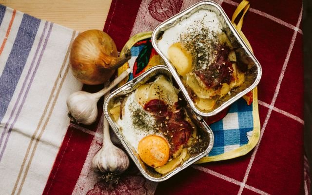 Delicious baked egg dish with vegetables in aluminum trays on a colorful tablecloth.