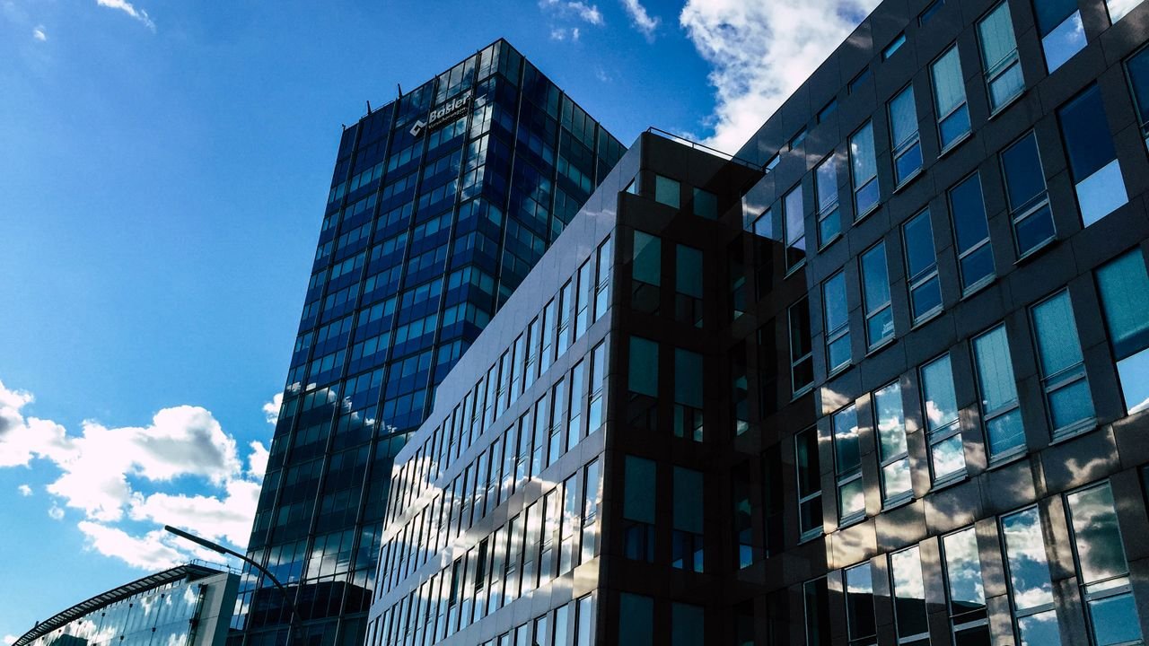 Contemporary skyscrapers with glass facades reflecting the sky and clouds on a sunny day.