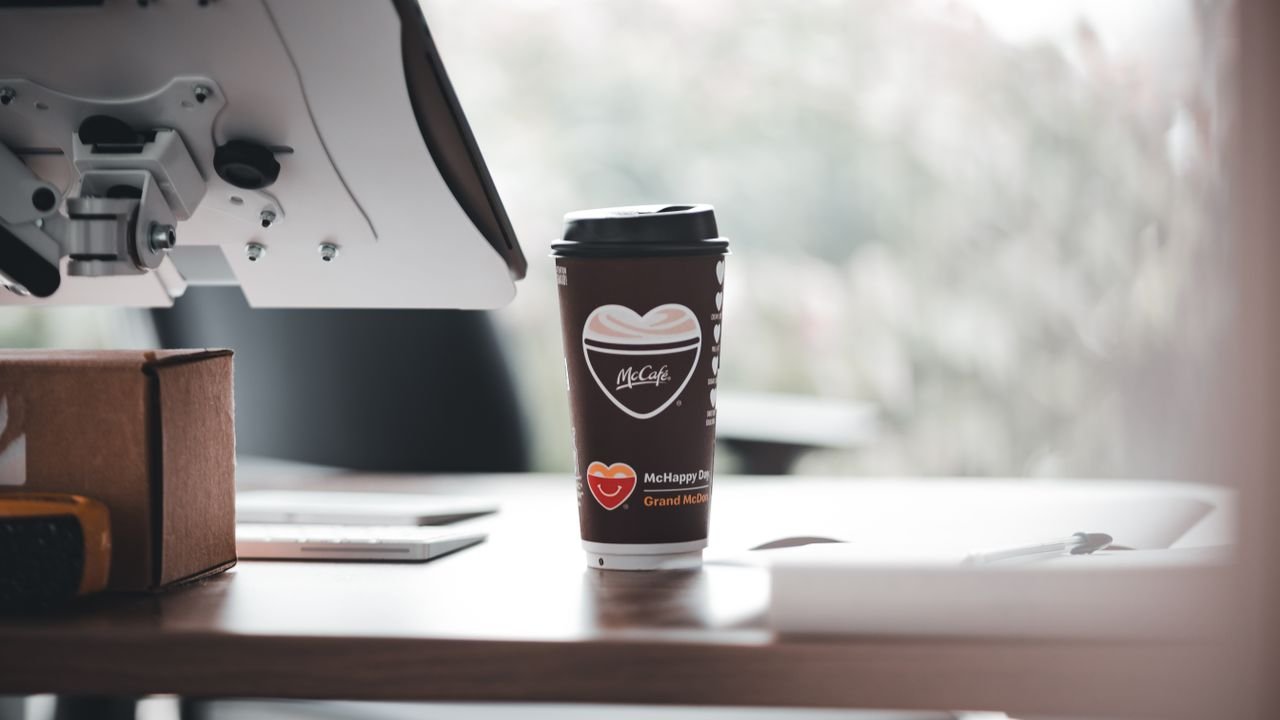 McCafe branded coffee cup on a modern office desk, creating a relaxed work ambiance.